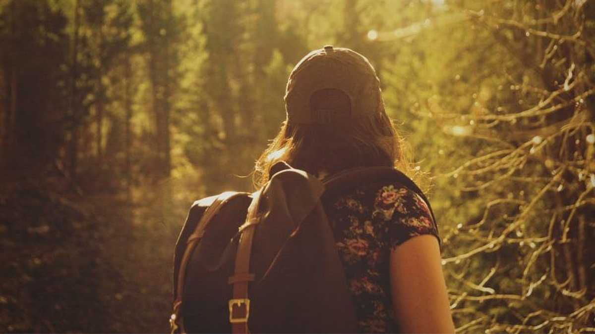 woman hiking outdoors with baseball cap and backpack